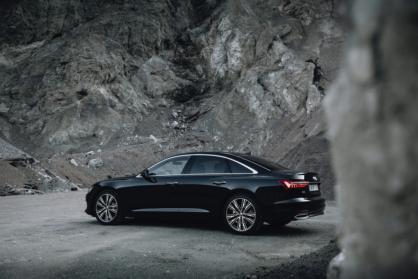 black sedan parked near gray rock formation